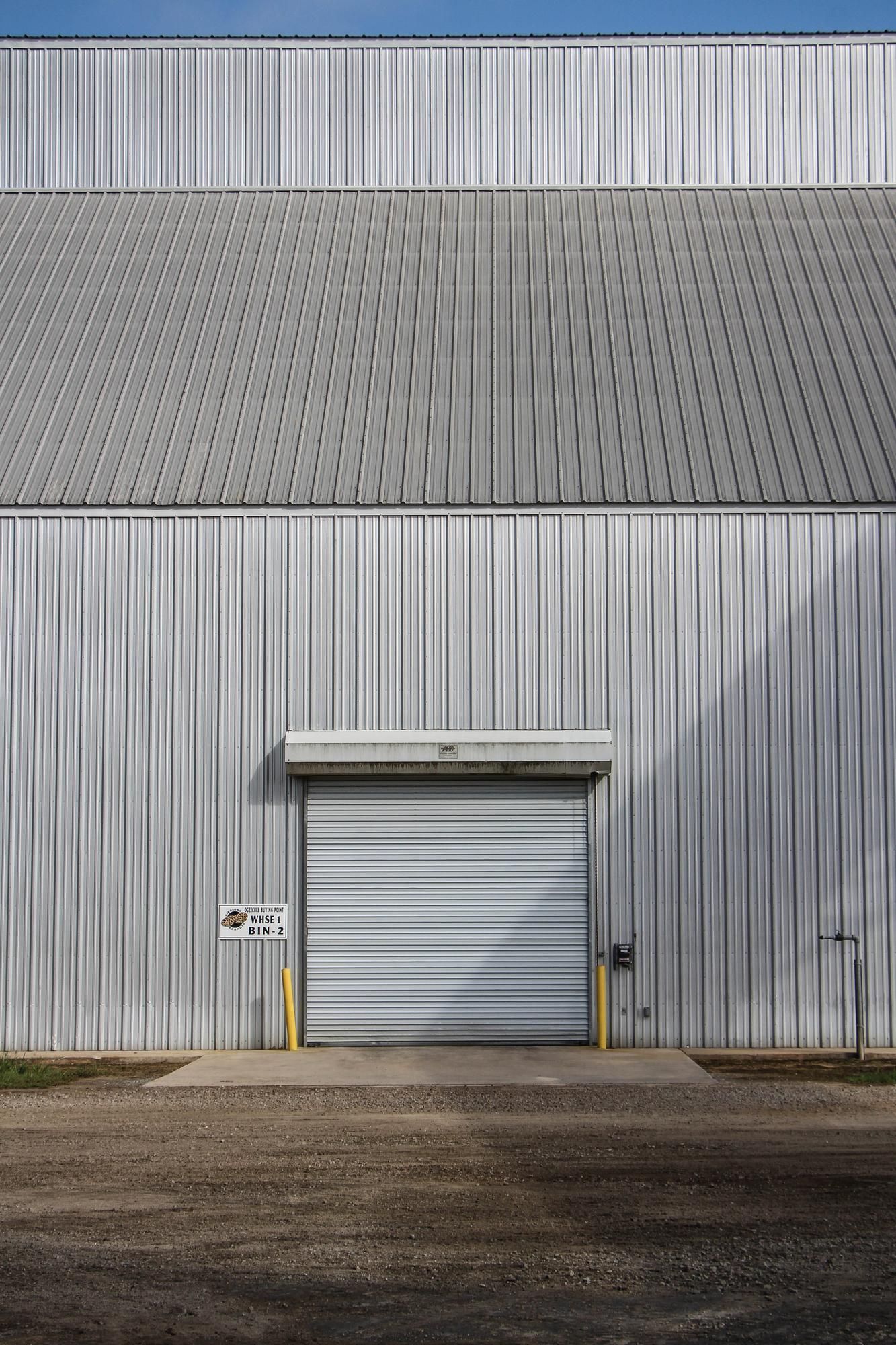 A large white building with a garage door and a blue sky in the background.