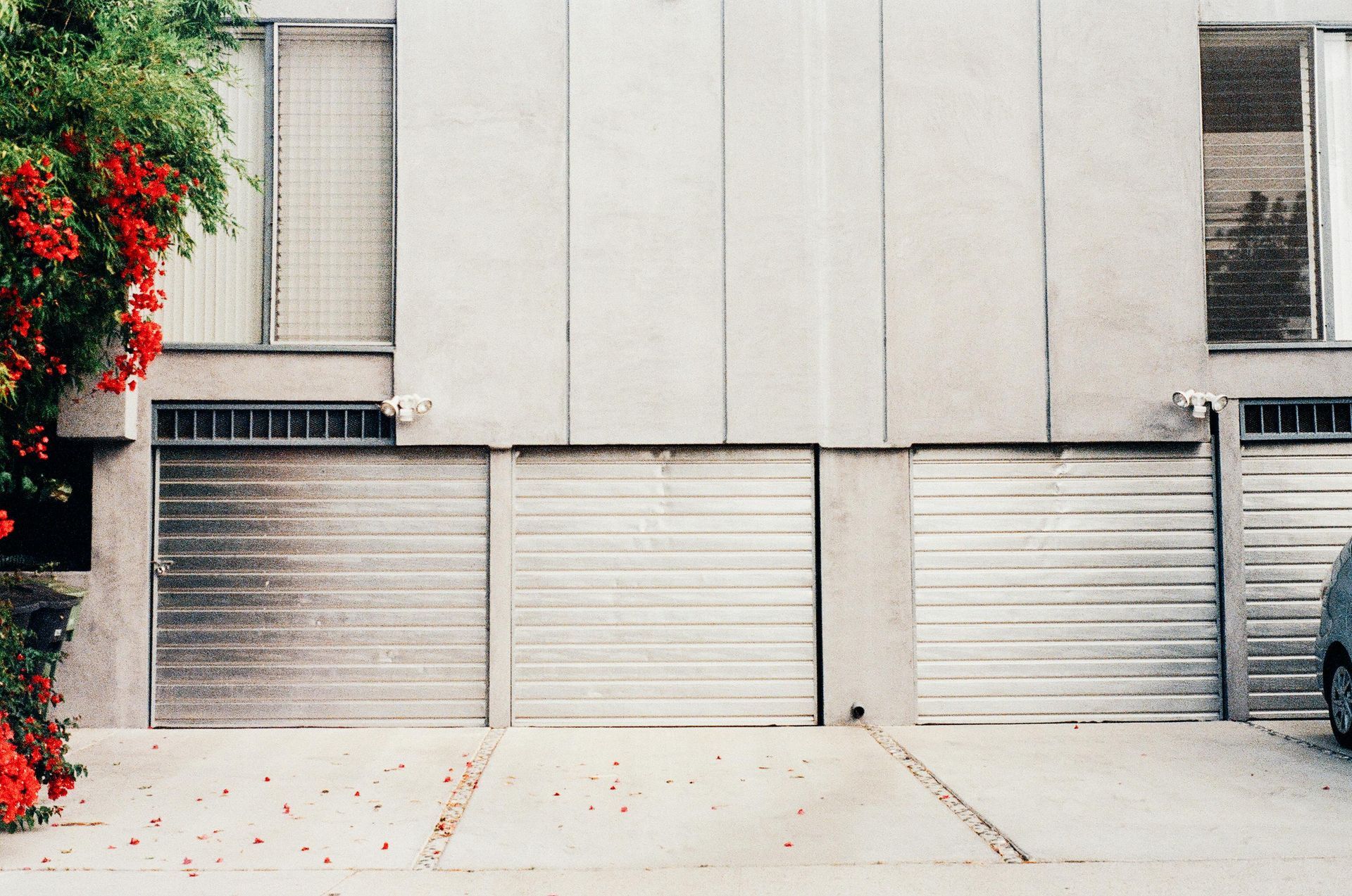A car is parked in front of a building with three garage doors