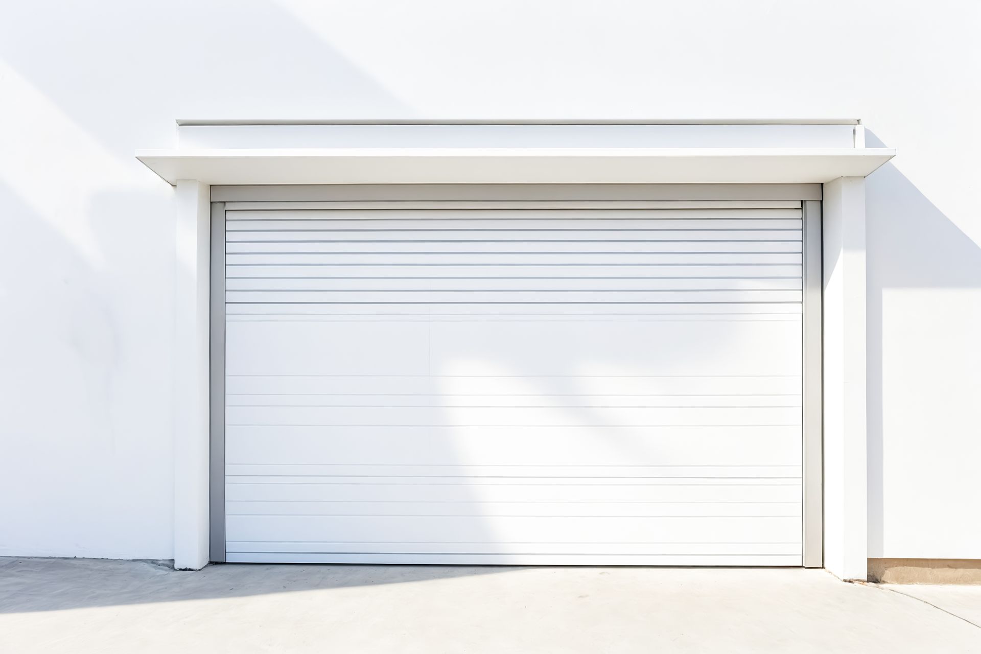 A white garage door is sitting on the side of a white building.