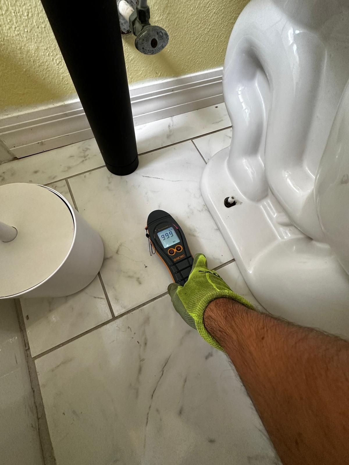 A person is standing next to a toilet in a bathroom.