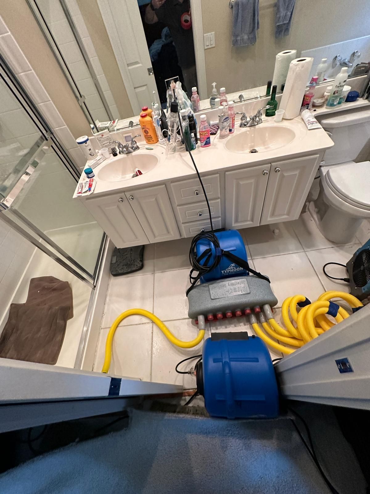 A bathroom with two sinks , a toilet , and a vacuum cleaner.