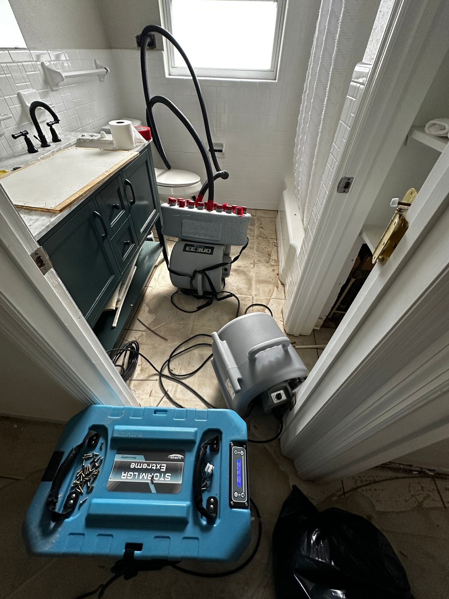 A bathroom with a vacuum cleaner sitting on the floor.