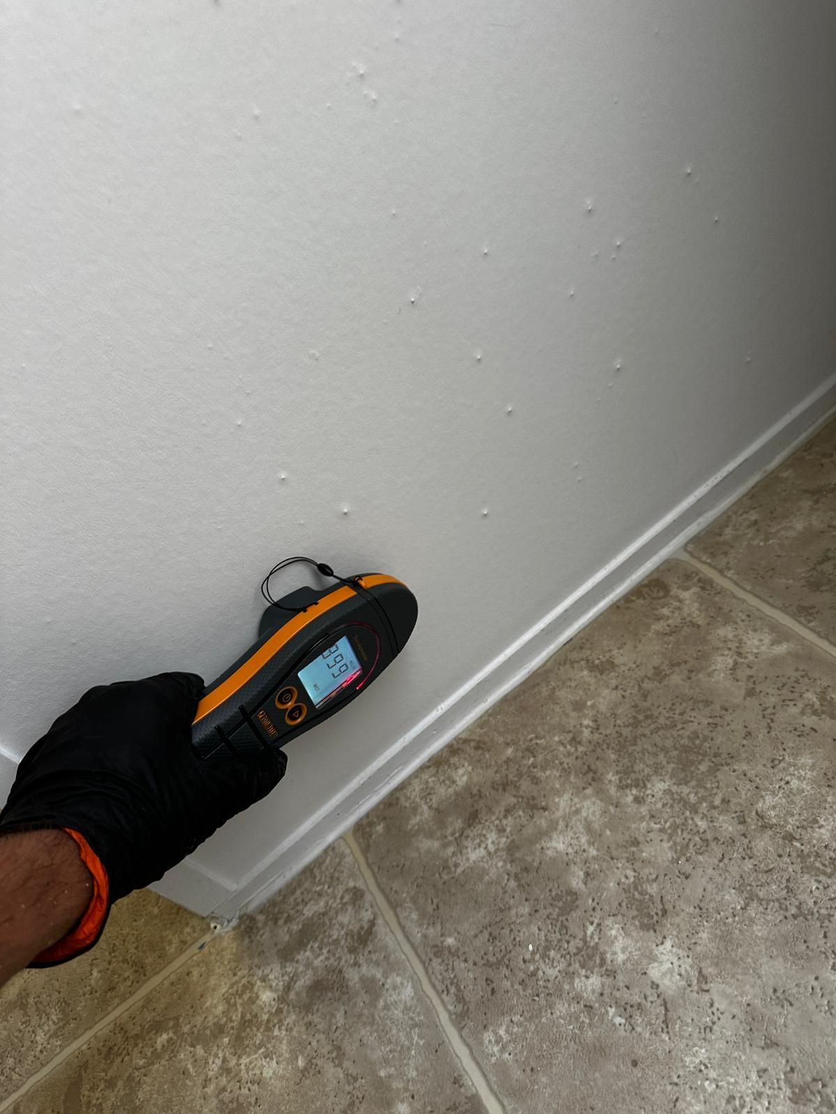 A person is measuring a wall with a tape measure.