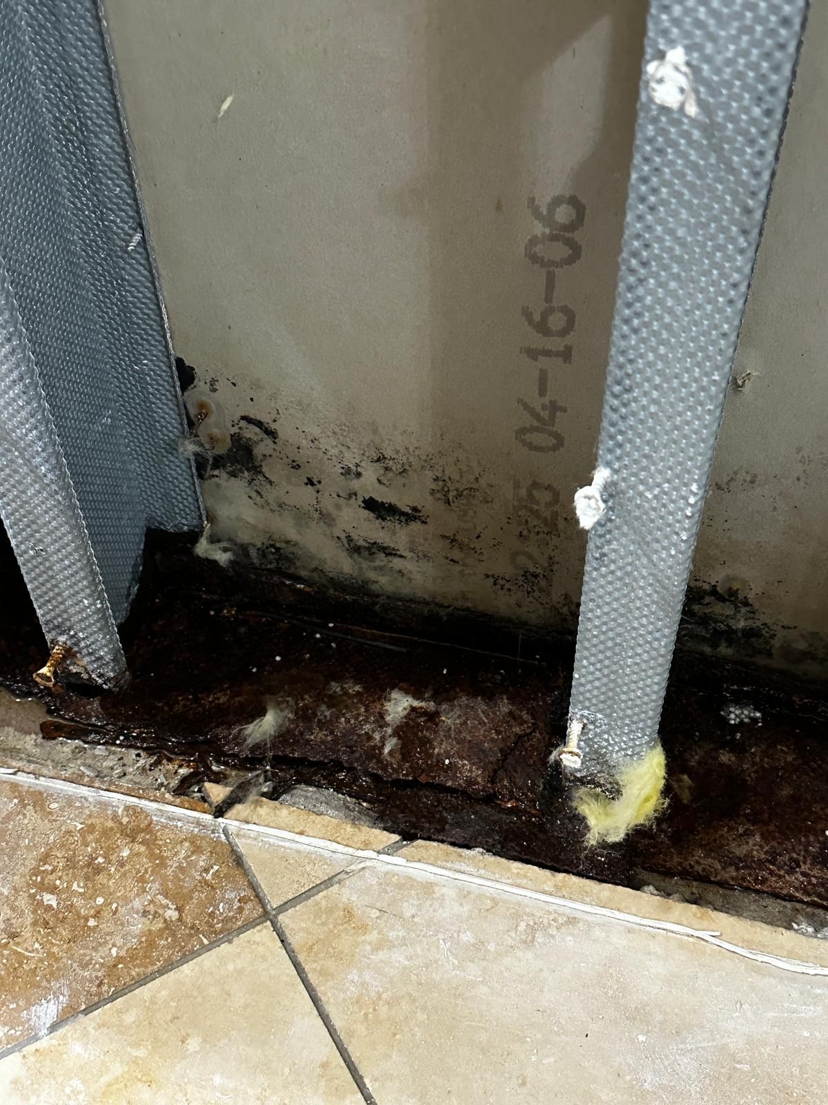 A dirty wall with a metal frame and a tile floor.