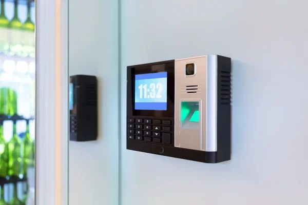 A fingerprint scanner is hanging on a wall next to a door.