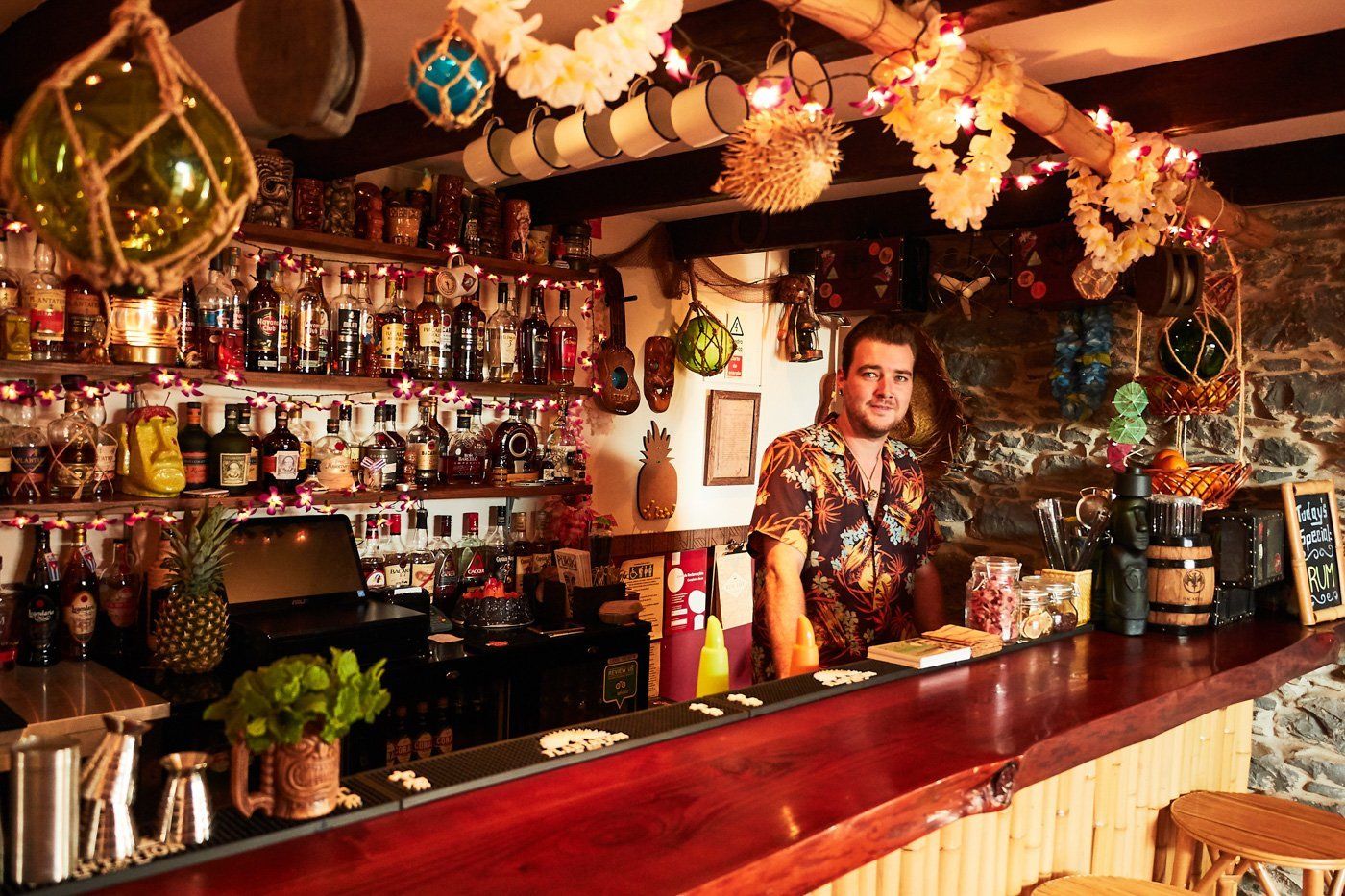 Martin Pukiki owner stands behind bar with rum selection in background