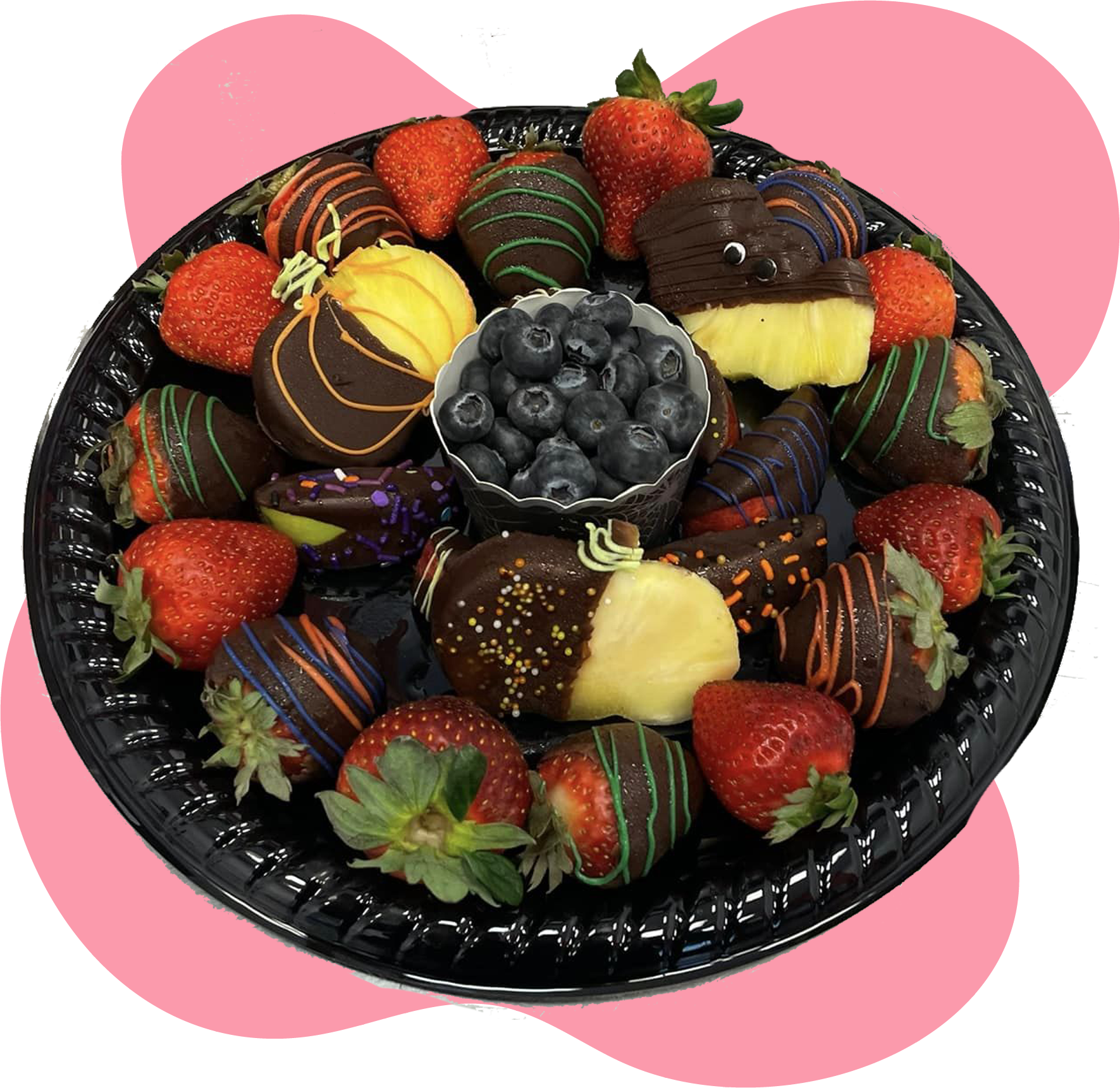 A black plate topped with chocolate covered strawberries and blueberries