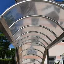 Arched, clear roof structure over a pathway, with metal supports.