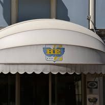 White awning with logo of a ship and clock over a window.