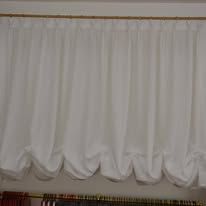 White, gathered, bubble-style curtain hanging from a gold rod.