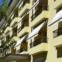 Yellow building with multiple balconies, white awnings, and metal railings.