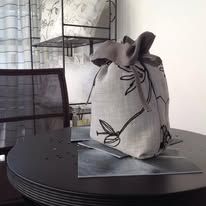 Gray drawstring bag with floral design on round black table.