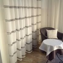 White curtains with gray horizontal stripes in a room with a chair and table.