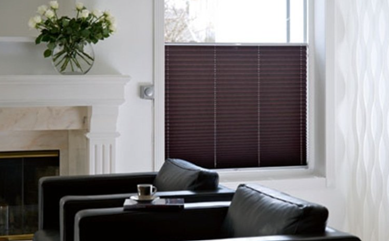 Living room with closed brown window blinds, two black chairs, and a white fireplace.
