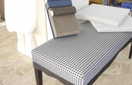 Bench with black and white checkered fabric, fabric samples, and white textured cushions.