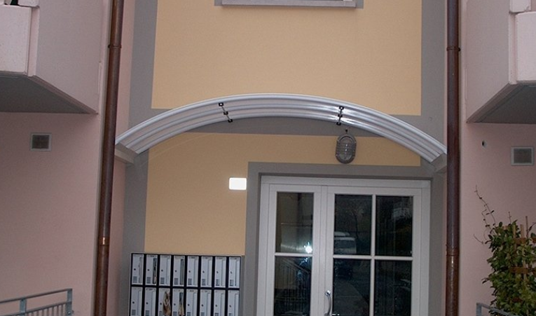 White arched awning above a glass door in a building entrance.
