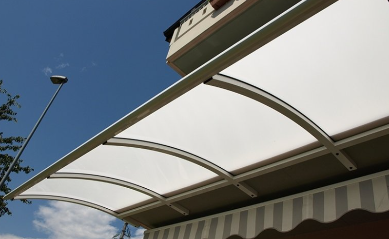 White canopy over a striped awning, against a blue sky.