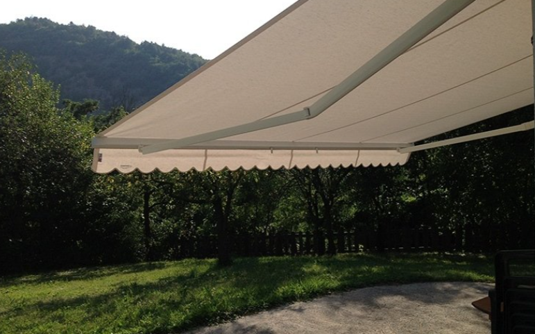 Cream-colored retractable awning over a patio, with trees and a mountain in the background.
