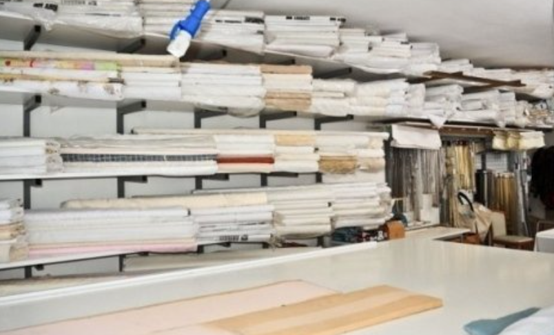 Shelves filled with stacks of fabric, in a workshop setting.