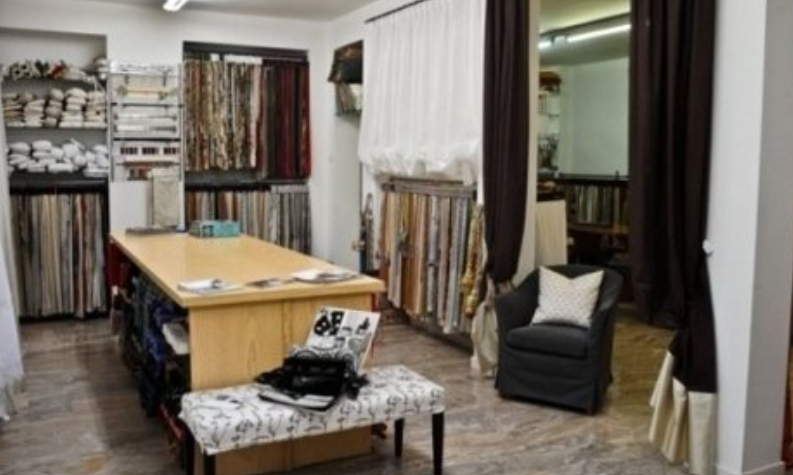 Fabric store interior with fabric swatches, bench, armchair, and central display table.
