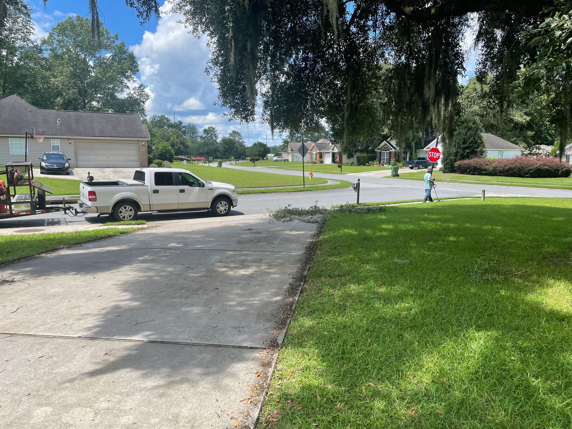 A white truck is parked on the side of the road in front of a house.