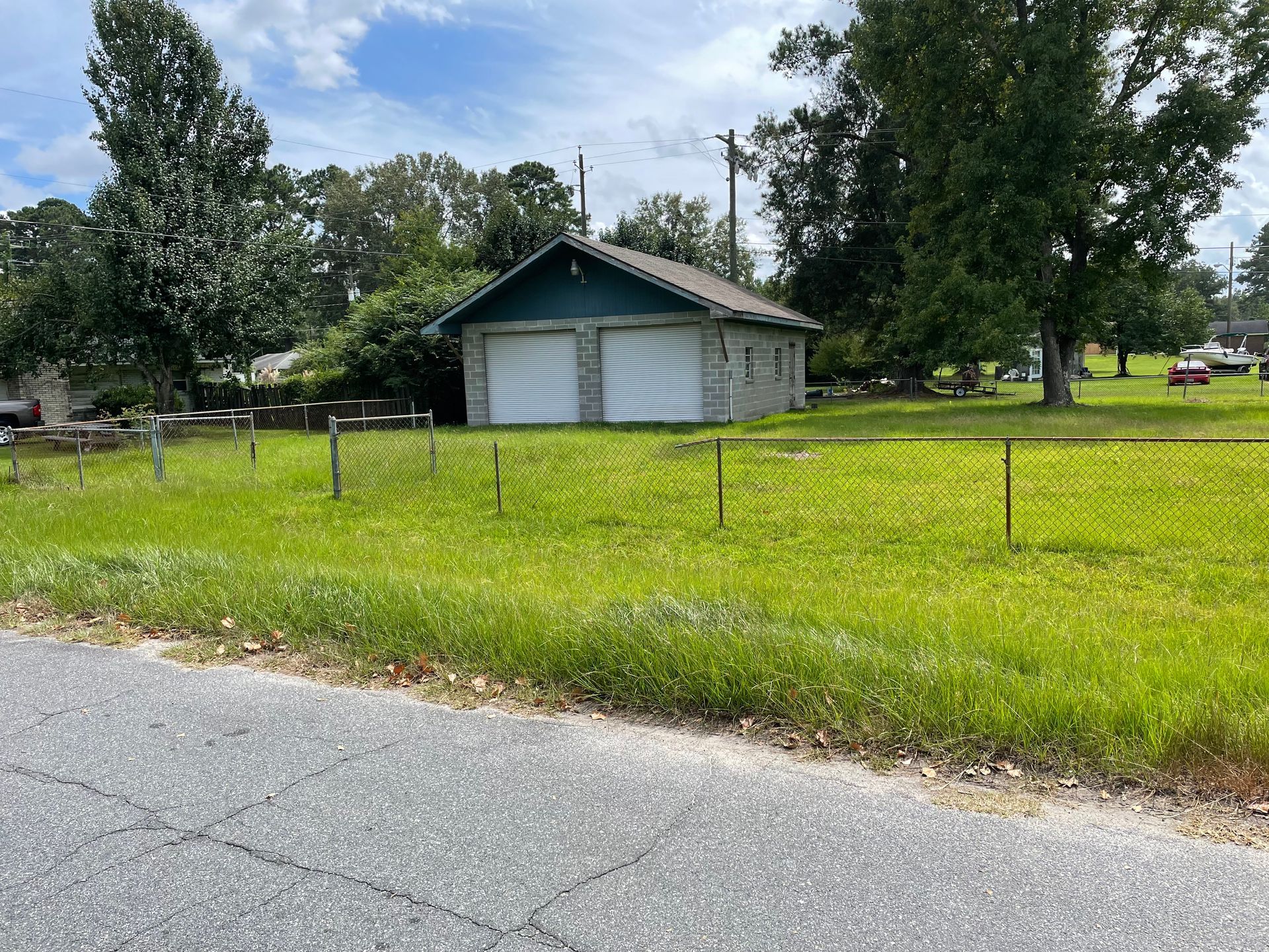 A garage is sitting in the middle of a grassy field next to a road.