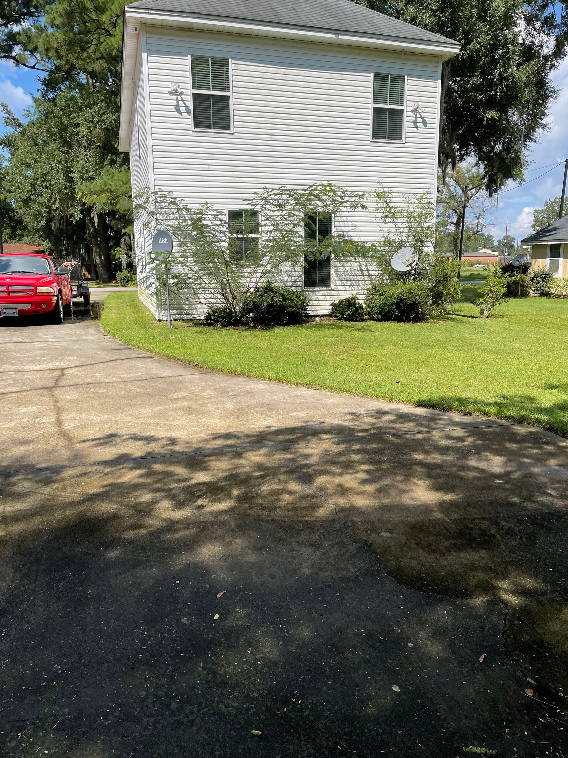 A white house with a red car parked in front of it.