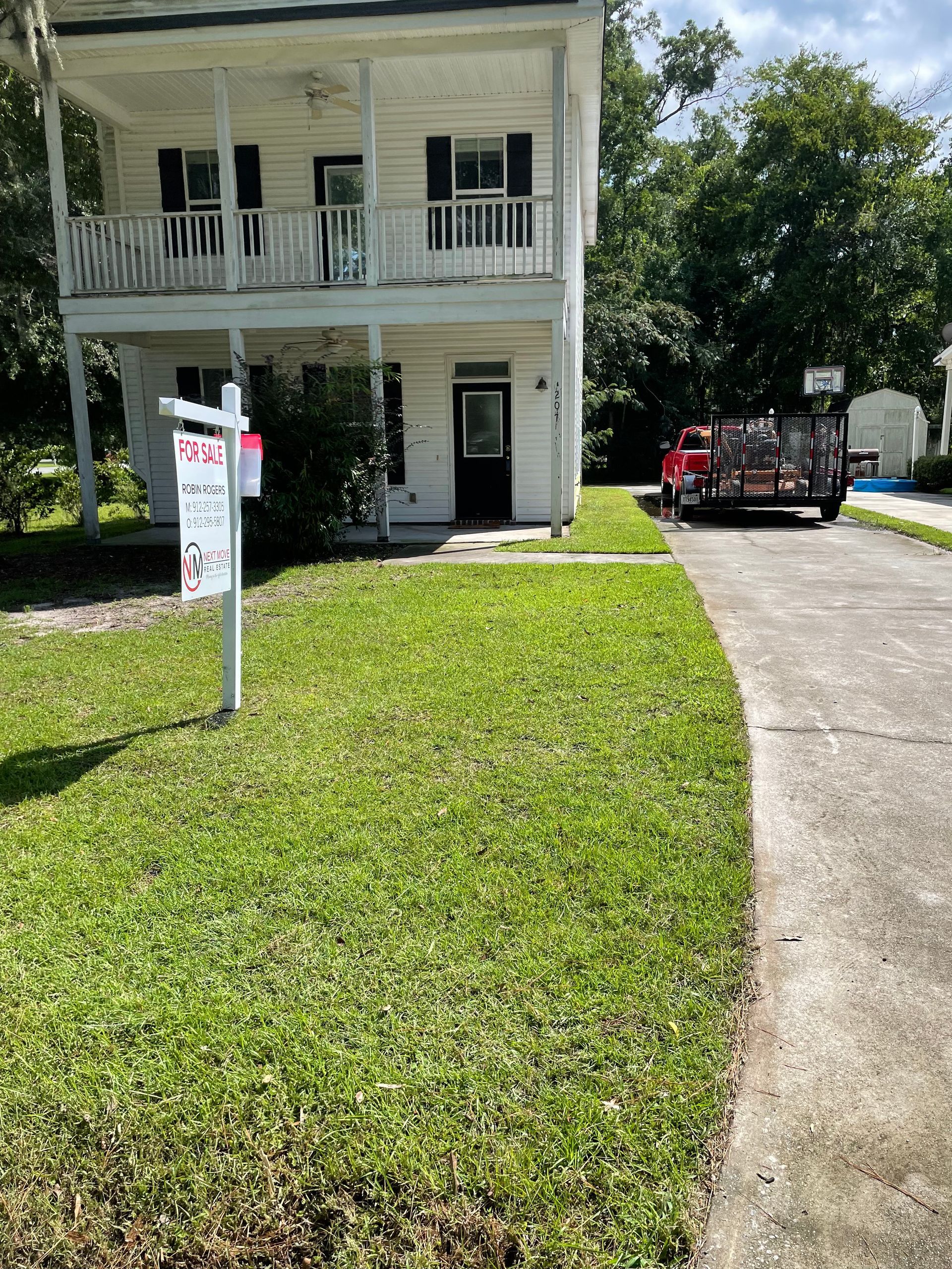 A large white house with a for sale sign in front of it.