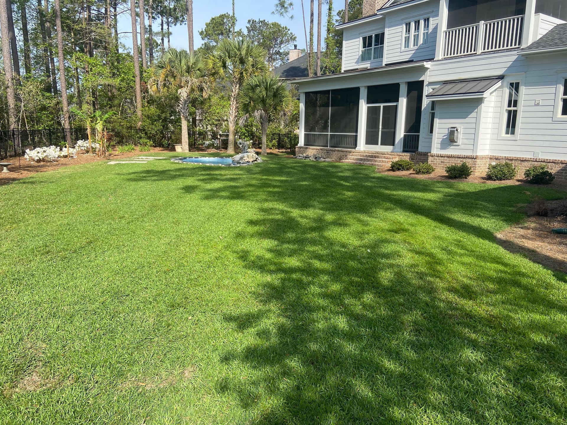 A large lawn in front of a house with a screened in porch.