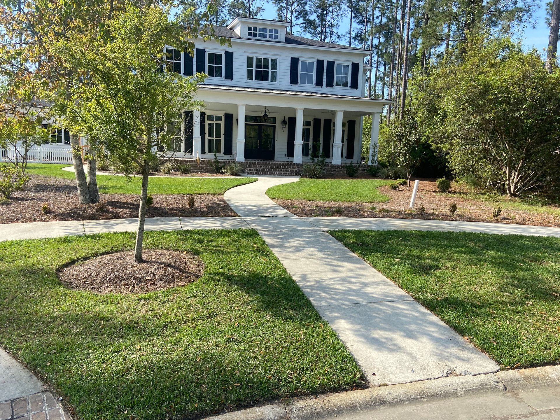 A large white house with a lush green lawn and a walkway leading to it.