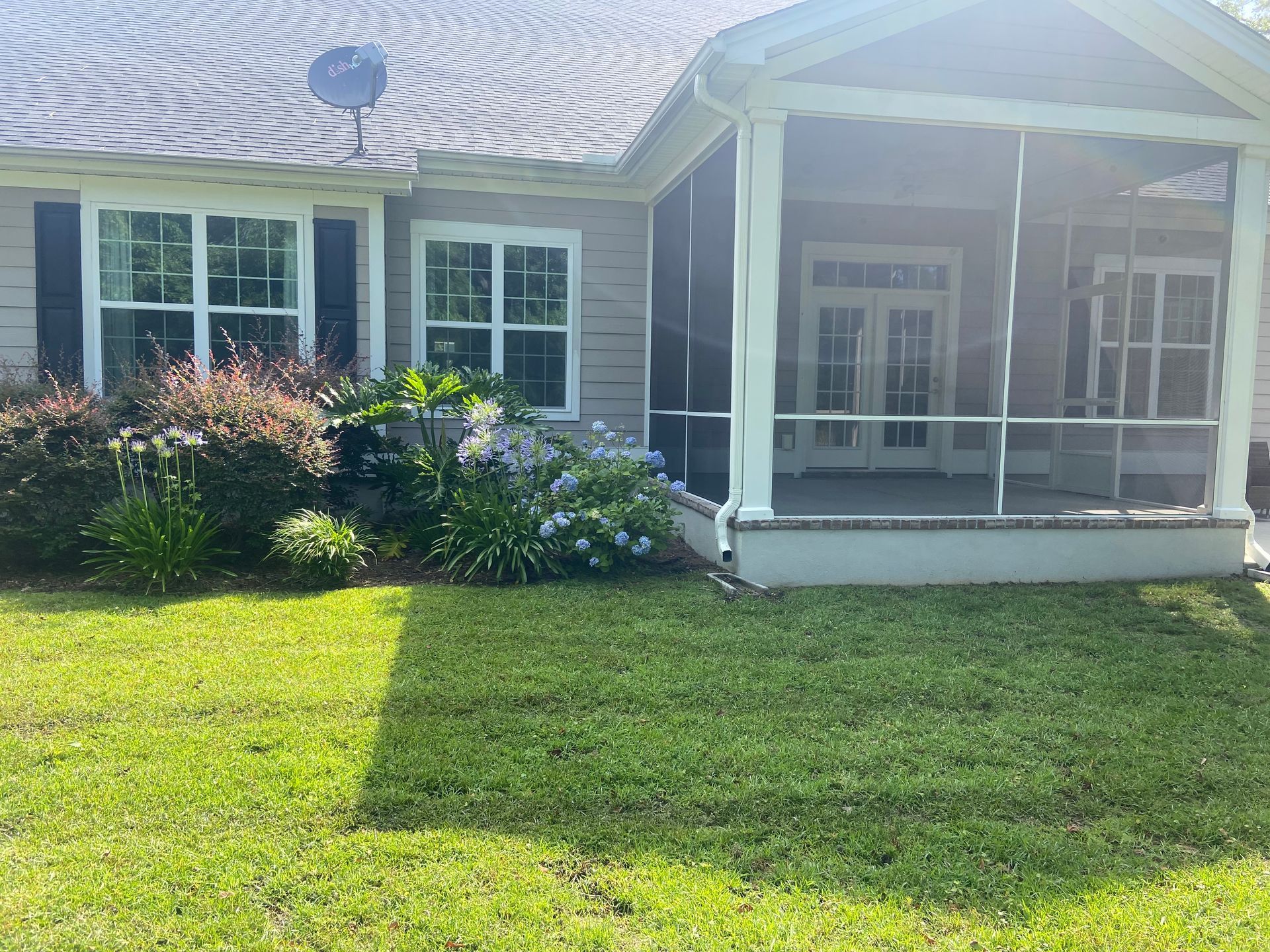 A house with a screened in porch and a satellite dish on the roof.