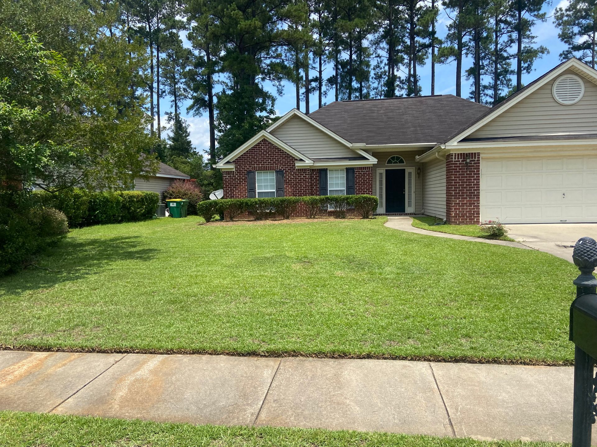 A house with a lush green lawn and trees in the background
