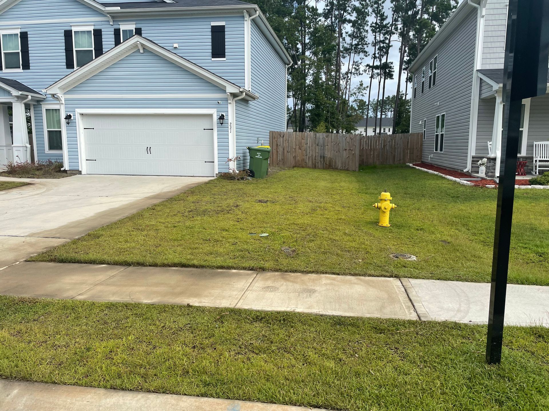 A yellow fire hydrant is in the grass in front of a house.
