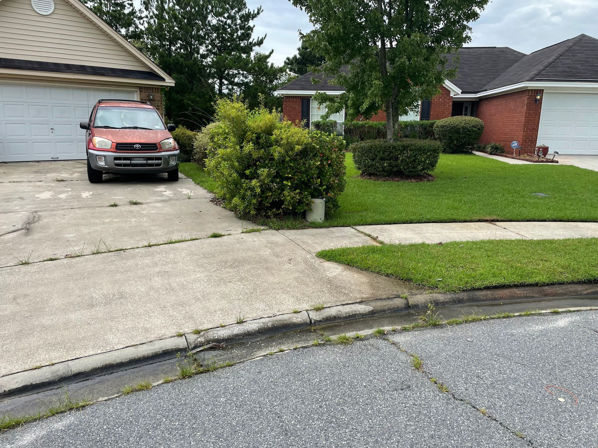 A red suv is parked in a driveway in front of a house.