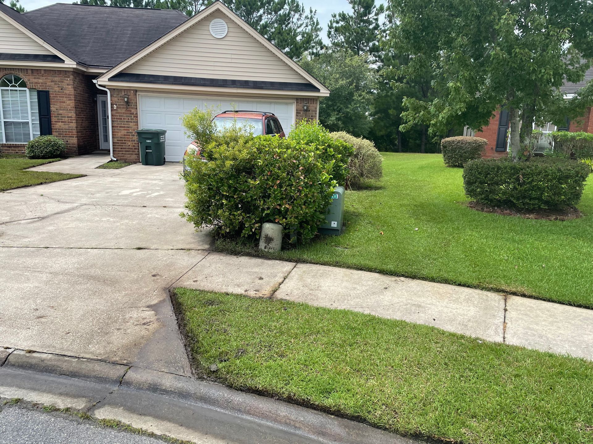 A house with a lush green lawn and a sidewalk in front of it.