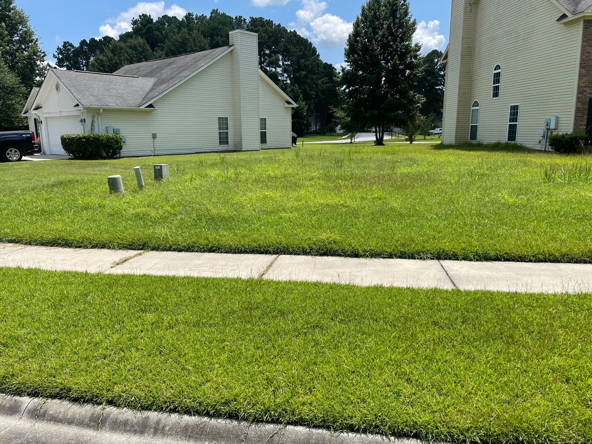 A lush green lawn with a white house in the background