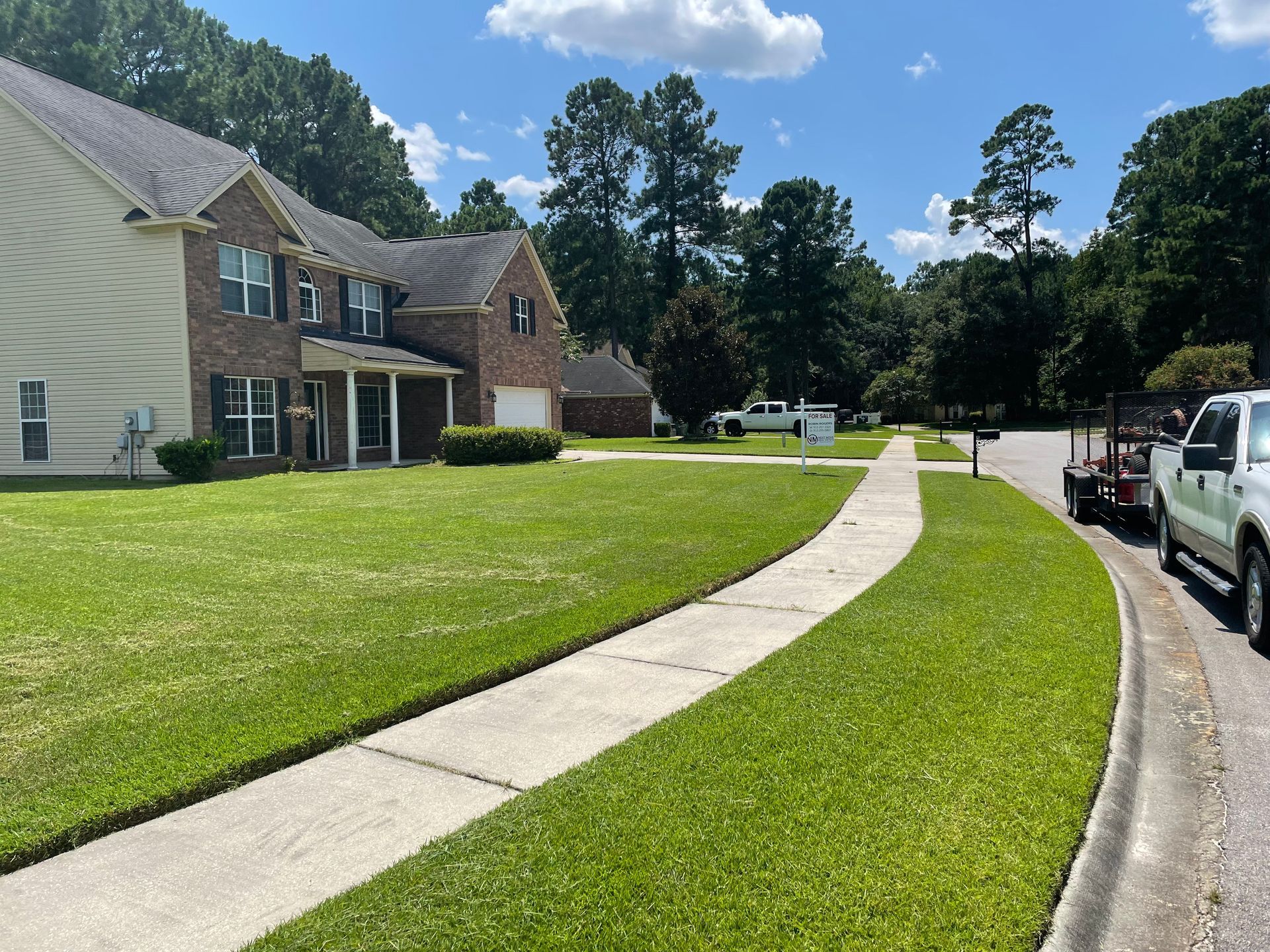 A lush green lawn with a brick house in the background