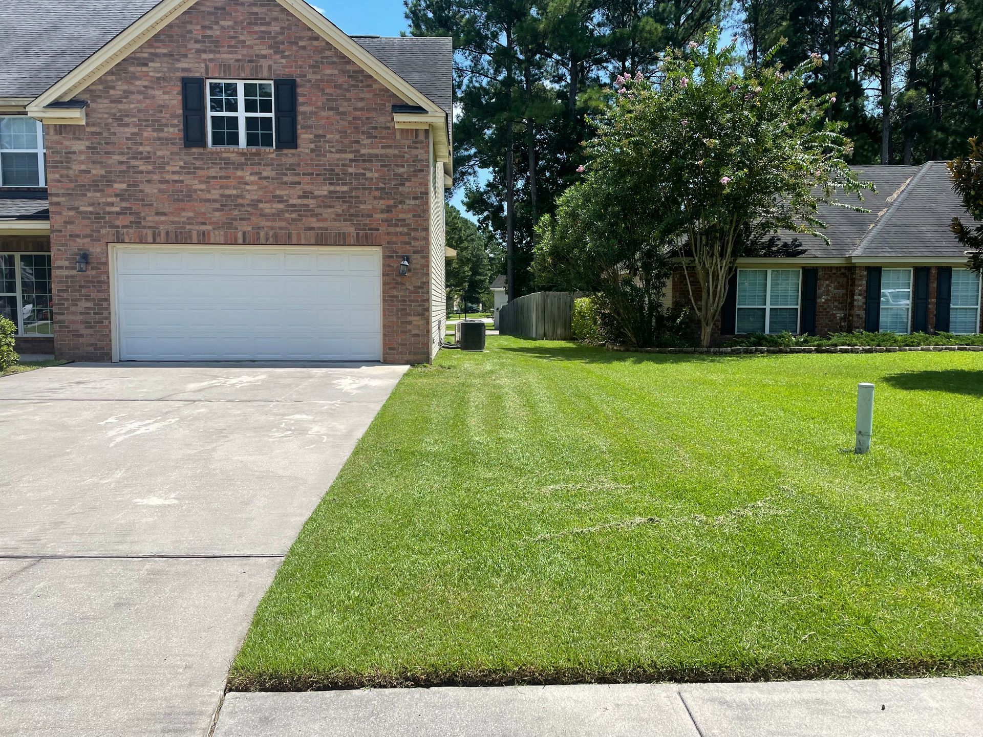 A brick house with a white garage door and a lush green lawn