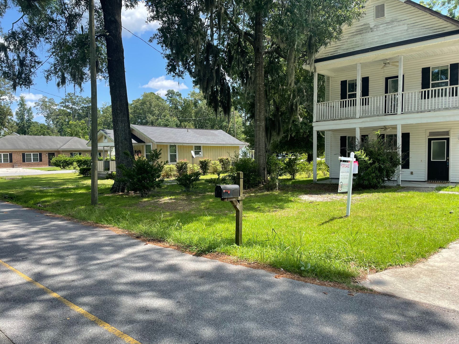There is a mailbox in front of a house that is for sale.