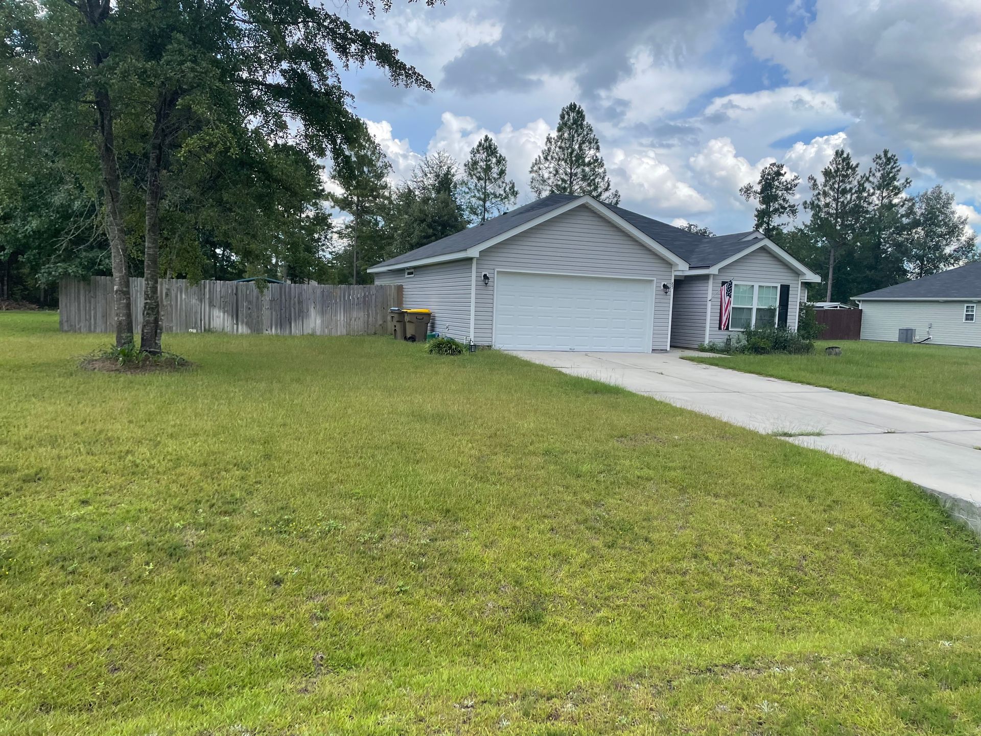 A house with a large garage and a fence in front of it.