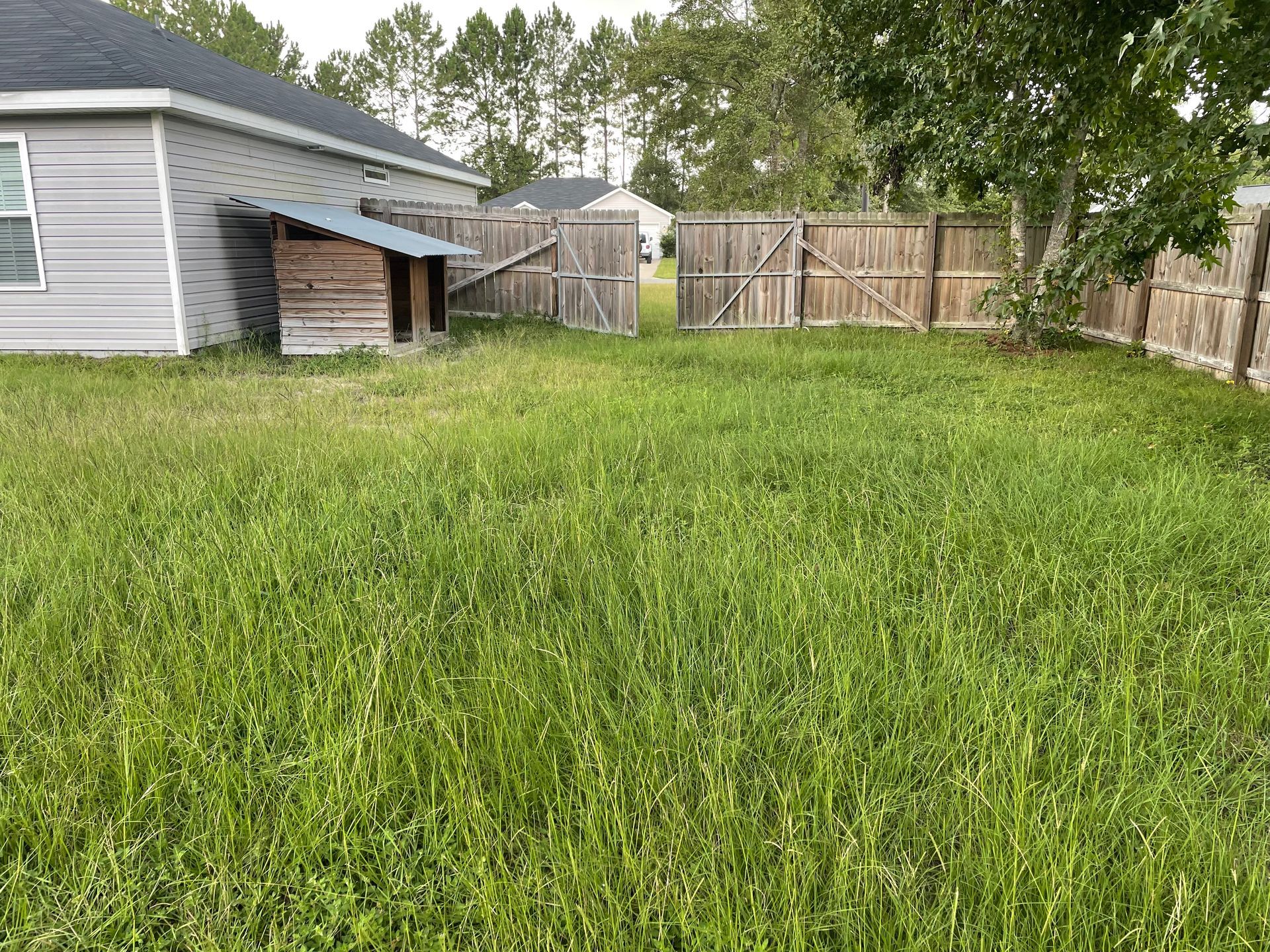 There is a dog house in the backyard of a house.