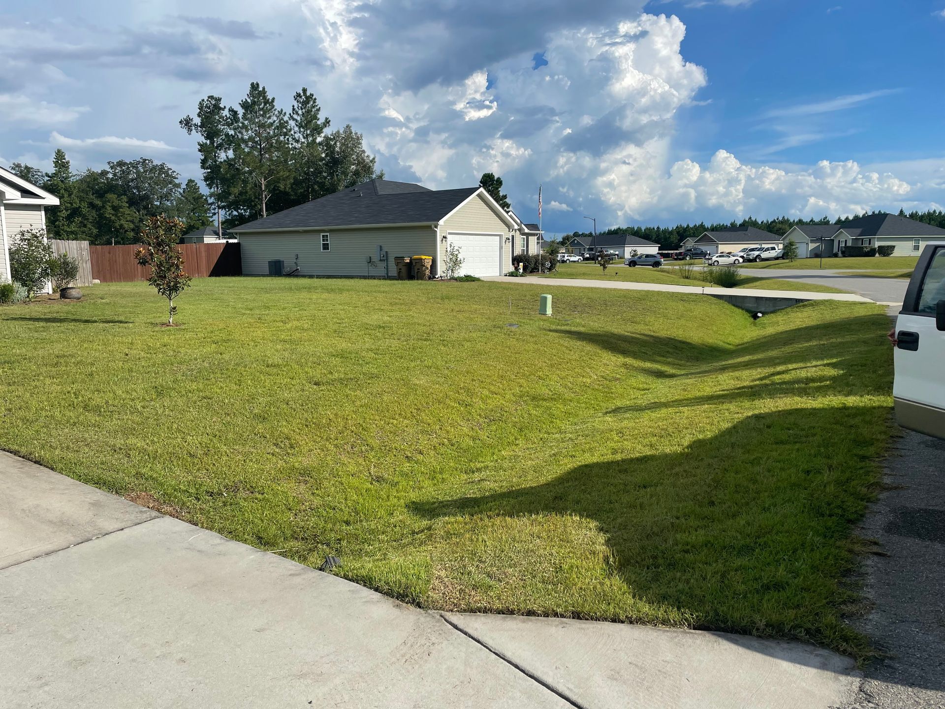 A white van is parked in front of a lush green yard.