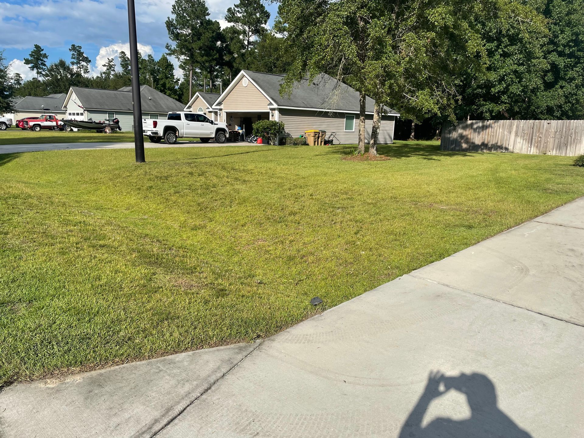 A person is taking a picture of a house from the sidewalk.