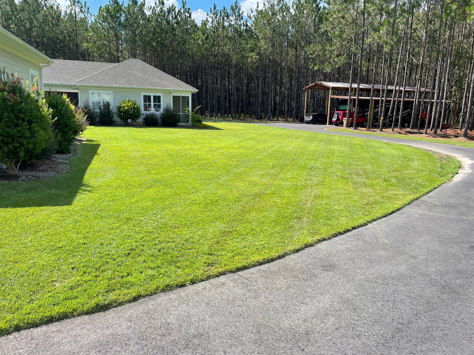 A house with a lush green lawn and a driveway leading to it.