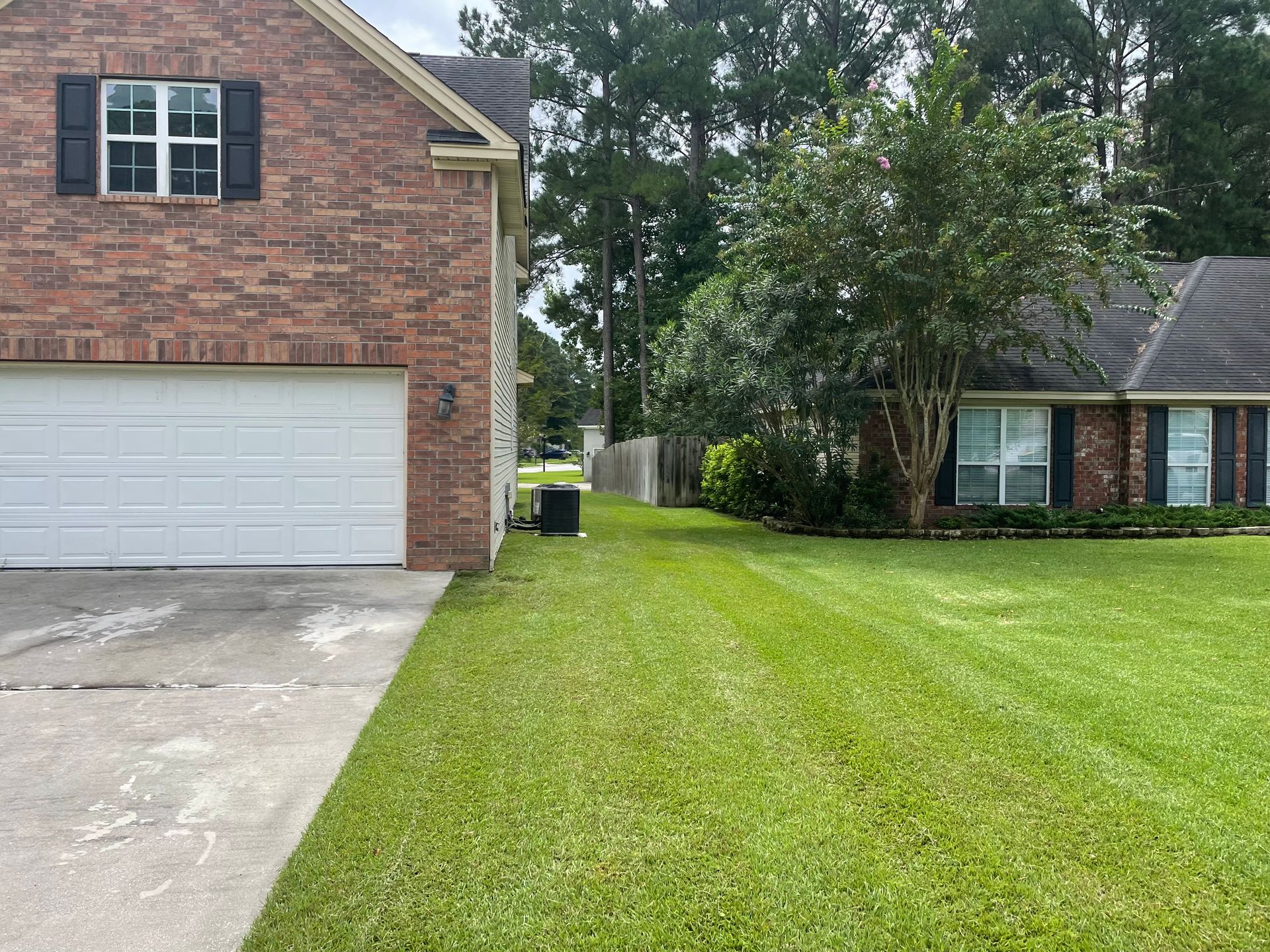 A brick house with a white garage door and a lush green lawn in front of it.