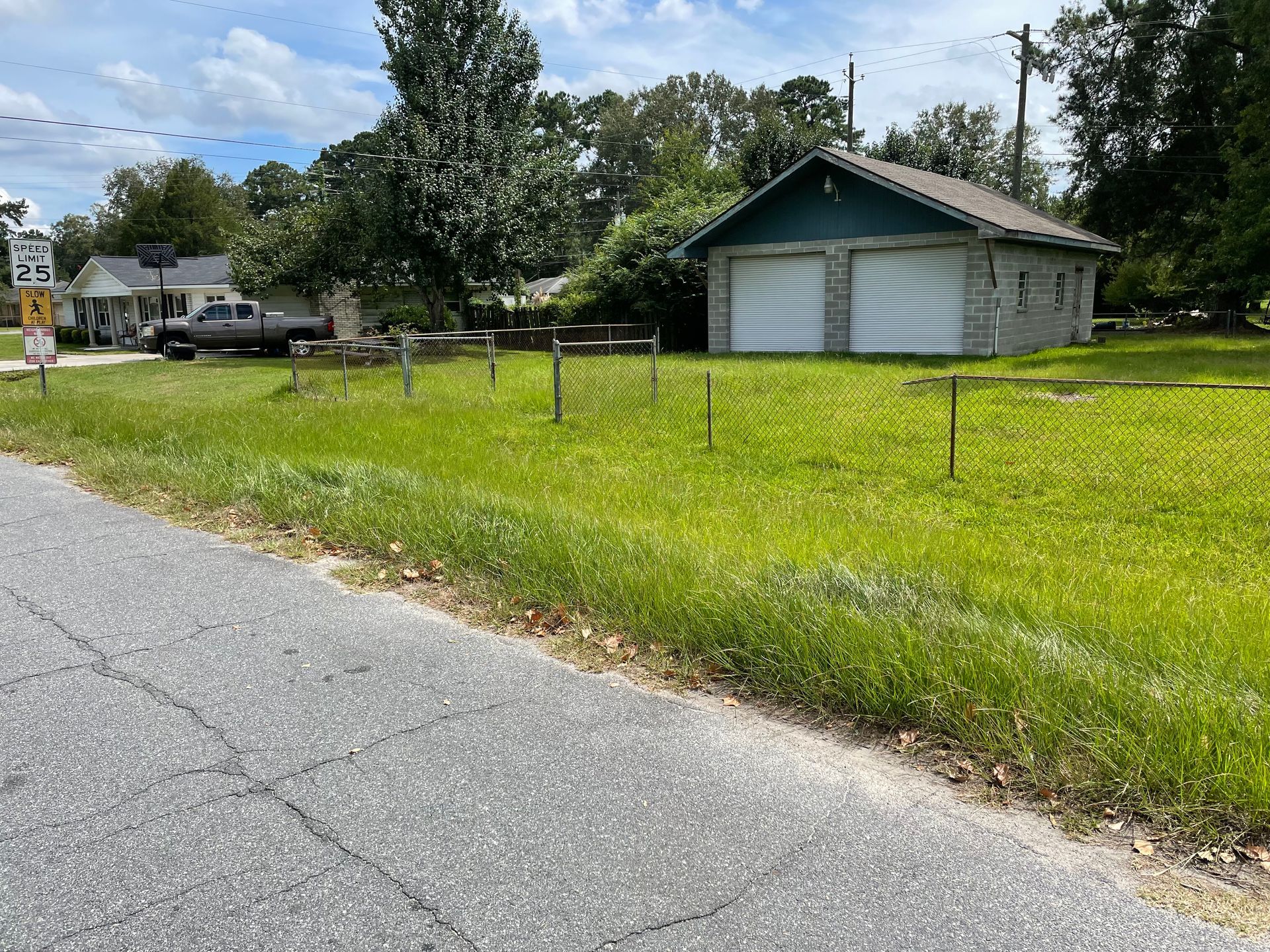 A house is sitting in the middle of a grassy field next to a road.