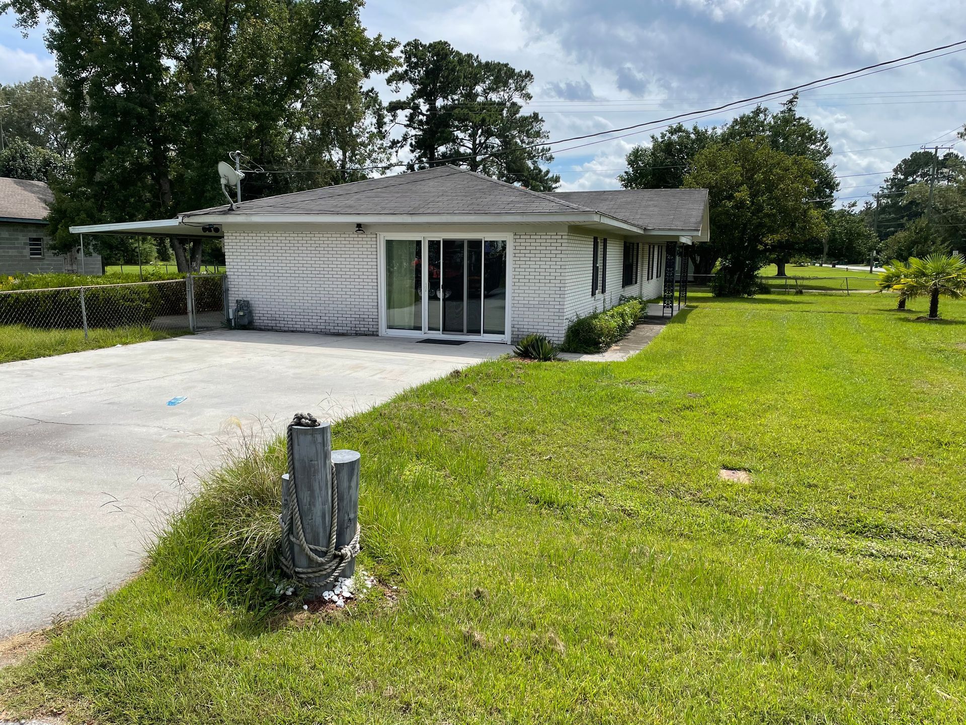 A white house is sitting in the middle of a lush green field.