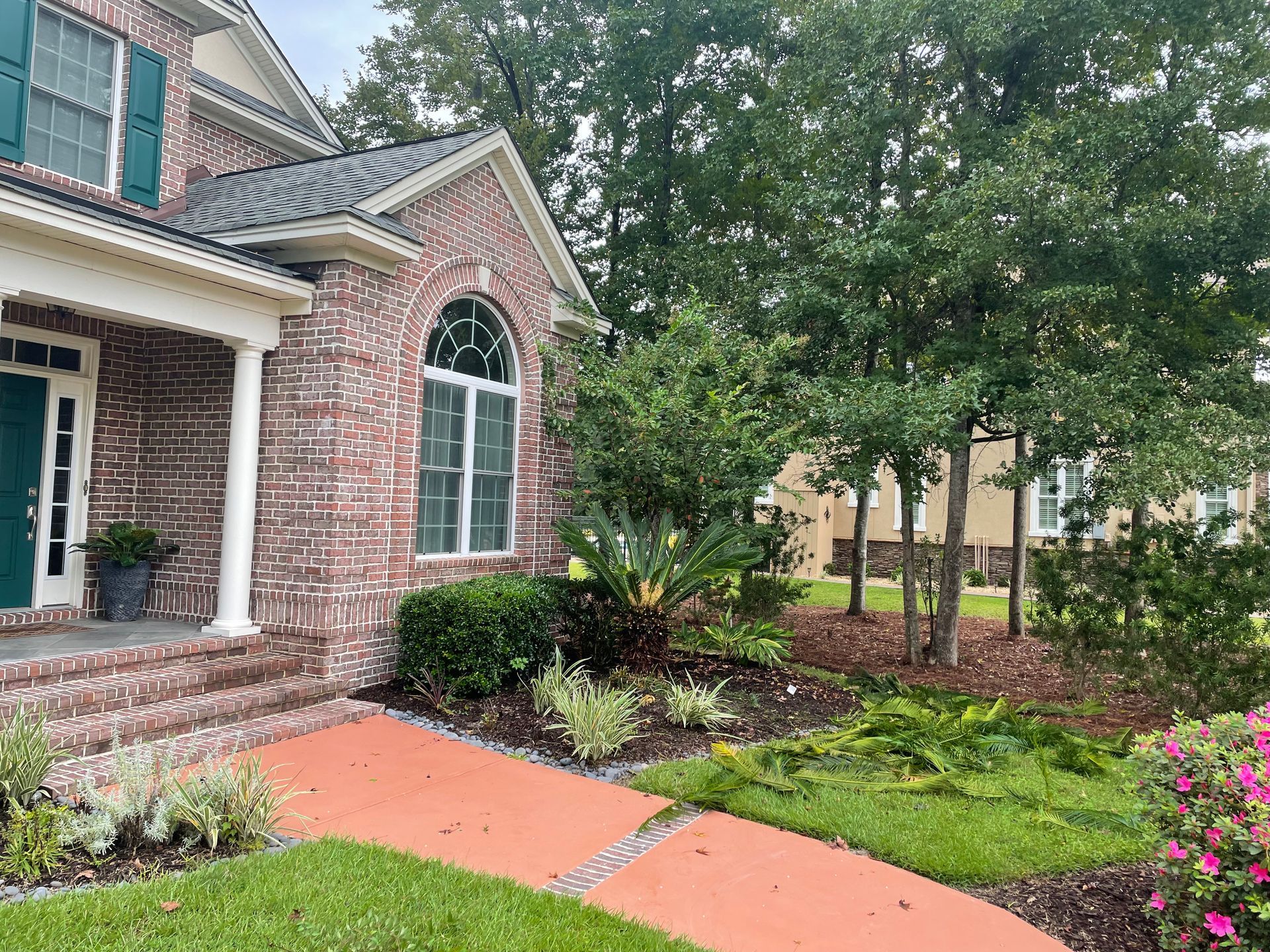 A brick house with a green door and a walkway leading to it.