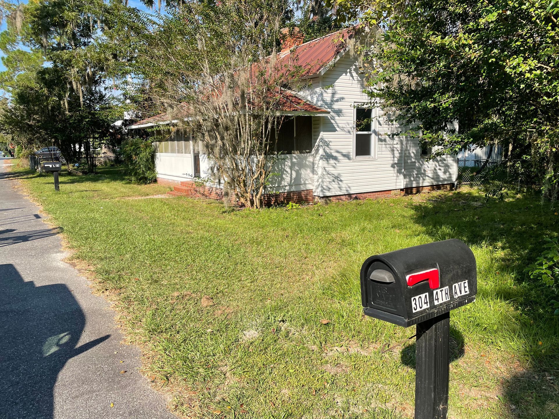 A black mailbox is in front of a white house.