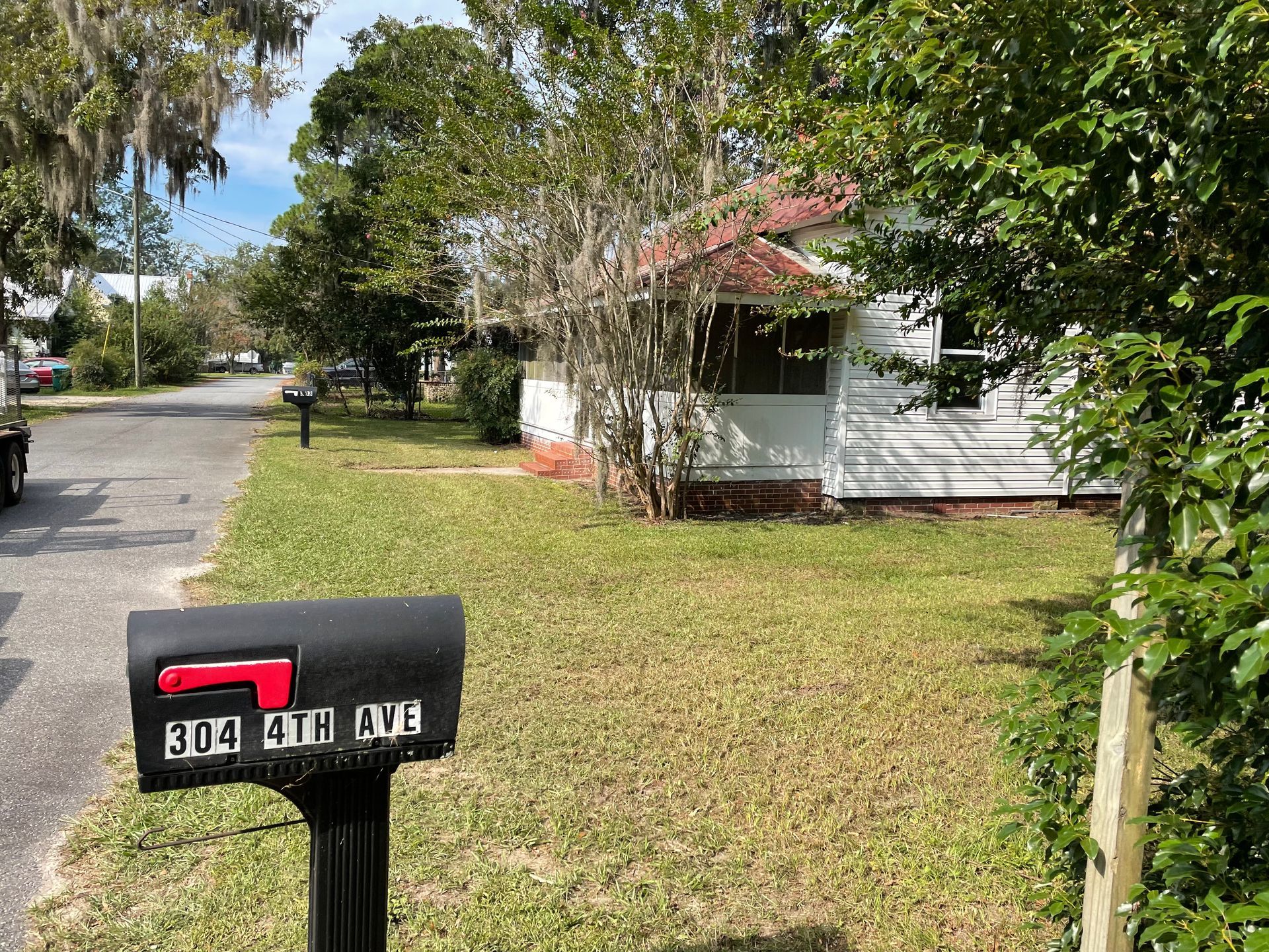 A mailbox is sitting in the grass in front of a house.